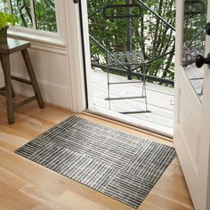 a door mat is on the floor next to a chair and table with a plant in it