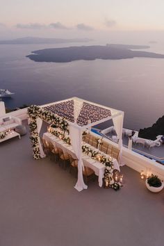 an outdoor wedding setup with candles and flowers on the table overlooking the ocean at dusk