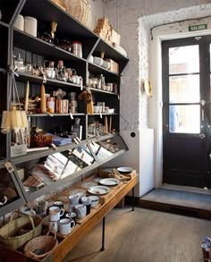 a store with shelves filled with dishes and baskets on it's sides next to a door