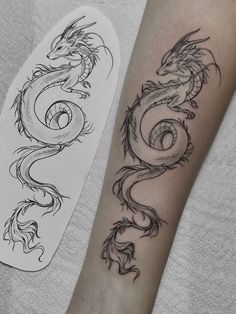 a black and white photo of a dragon tattoo on the arm