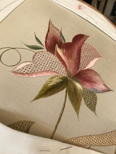 the back of a chair with a flower on it's seat and some fabric