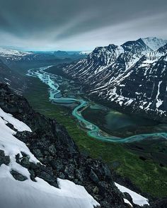 an aerial view of a river running through snow covered mountains