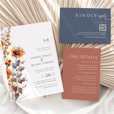 the wedding stationery is laid out on a white plate with an orange and blue flower