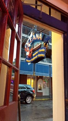 an open door to a restaurant with cars parked outside it and the sign on the building