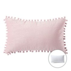 a pink pillow with pom - poms on it and a white pillow in the background