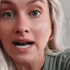 a woman with blonde hair and blue eyes is looking at the camera while brushing her teeth