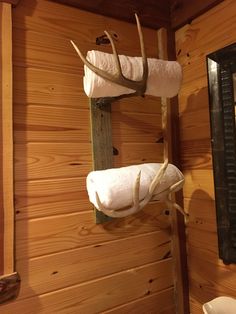 two white towels are hanging from a rack in a bathroom with deer antlers on the wall