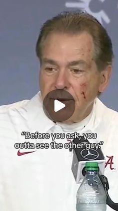 a man with blood on his face sitting in front of a microphone and holding a water bottle