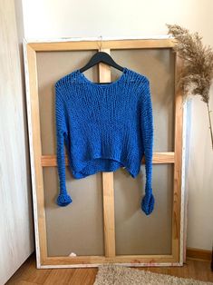 a blue sweater hanging on a wooden frame