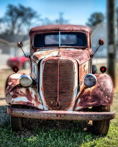 an old rusted out truck sitting in the grass