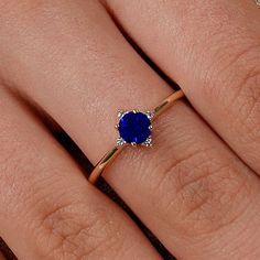 a woman's hand with a ring on it and a blue stone in the middle