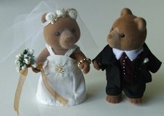 two teddy bears dressed in wedding attire standing next to each other on a white surface