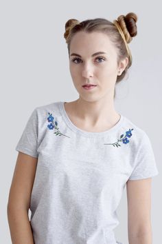 a young woman wearing a white t - shirt with blue flowers on the front and side