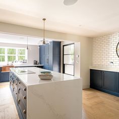 a large kitchen with blue cabinets and white counter tops, along with an island in the middle