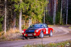 a red and black car driving down a dirt road