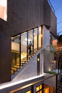 the stairs lead up to the upper level of this modern house at night, with two people walking down it