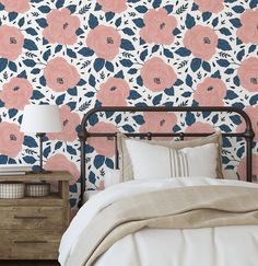 a bedroom with pink and blue flowers on the wall next to a bed in front of a night stand