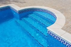 an empty swimming pool with blue water and tile border around the edge is seen from above