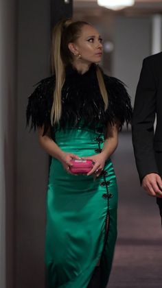 a woman in a green dress and a man in a tuxedo walking down a hallway