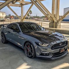 a silver mustang car parked under a bridge