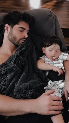 a man laying on top of a couch holding a baby