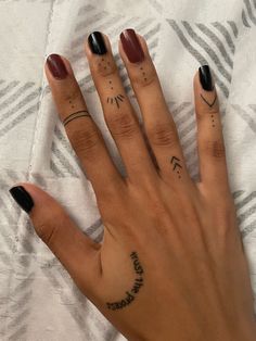 a woman's hand with two small tattoos on her left thumb and the middle finger