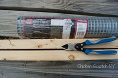 a pair of pliers sitting on top of a piece of wood next to a roll of duct tape