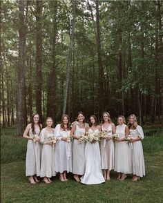 a group of women standing next to each other in front of trees