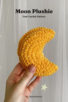 a hand holding a yellow crochet moon plushie