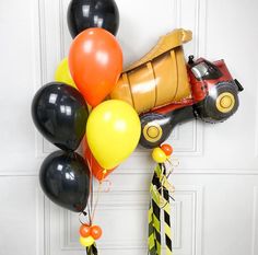 a construction themed birthday party with balloons and streamers on the front door, including a dump truck