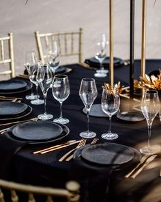 the table is set with black linens and gold place settings for an elegant dinner