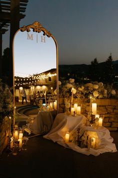 a mirror sitting on top of a table covered in flowers and candles next to a bunch of lit candles