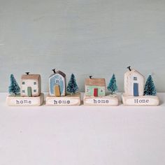 small wooden houses with trees on them and the words home are painted in different colors