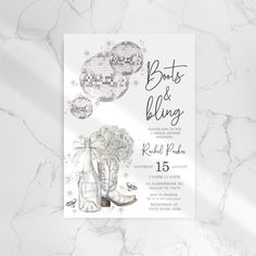 the boots and blingb wedding card is shown on a marble surface with white flowers