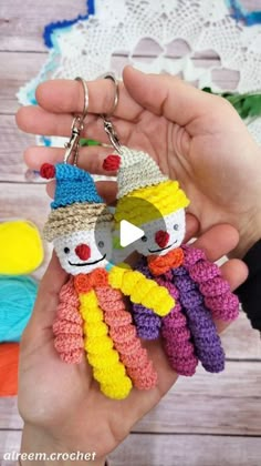 someone is holding two small crocheted dolls in their hands, one wearing a hat and the other as a scarecrow