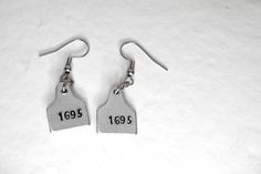 "Cattle tag earrings, tiny 1/2\" cow tag earrings, personalized, hand stamped with the numbers or up to 4 letters you choose. These earrings are made with lightweight aluminum and hang from stainless steel ear wires. The 1/2\" cow tag earrings make a great gift for the 4H animal show with the number of your favorite animals.              All Jewelry is made to order.   Hand Stamped Jewelry can have flaws and misalignments, each piece is unique and may have a slight difference than pictured.      Your purchase will be shipped in a gift box ready for giving." Human Cow, Cow Tag Earrings, Number Earrings, Cattle Tags, Metal Cow, Cow Tag, Earrings Western, Gifts For Daughter, Jewelry Ear