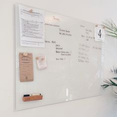 a white board with notes on it next to a potted plant