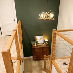 two wooden stairs leading to a bedroom with green walls and white carpeted flooring