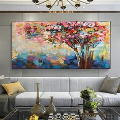 a living room filled with furniture and a large painting on the wall over a coffee table