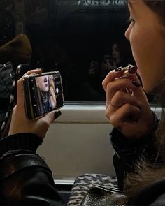 a woman taking a photo with her cell phone on the subway car while she's riding