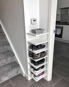 there is a shelf with shoes on it in the corner next to stairs and carpet