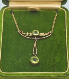 "Antique Art Nouveau Edwardian 9k Two-Tone Gold Peridot Dangling Pendant Necklace with a floral motif circa 1905 with a matching antique green felt necklace box! Necklace length is 19\" (including the pendant piece). We can always remove links in the necklace to reduce the length before shipping! The top pendant is 1.25\" long. The dangling pendant piece is 1.1\" long. The piece in total weighs 5.1 grams. The pendant is marked 9ct and the necklace is marked 9kt. In excellent antique condition. F Art Nouveau Yellow Gold Jewelry With 17 Jewels, Art Deco Yellow Gold Necklace For Formal Occasions, Art Nouveau Yellow Gold Jewelry For Formal Occasions, Gold Art Nouveau Necklace With Gemstone, Art Nouveau Gold Necklace With Gemstone, Art Nouveau Yellow Gold Necklace For Formal Occasions, Elegant Engraved Necklace With May Birthstone, Art Nouveau Yellow Gold Formal Necklace, Art Nouveau Pendant Jewelry For Formal Occasions