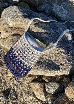 a crocheted bag sitting on top of a rock covered in dirt and rocks