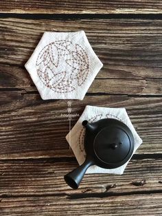 two tea towels and a black pot on a wooden table with an iron skillet