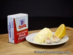 a white plate topped with food next to a carton of butter and a lemon wedge