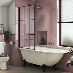 a white bath tub sitting next to a toilet in a bathroom with pink walls and flooring