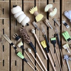 several different types of kitchen utensils laid out on a wooden table with black and white handles