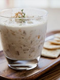 there is a small glass with some food in it on the tray next to crackers