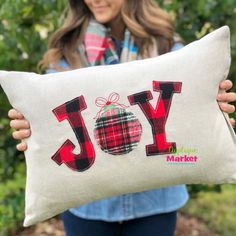 a woman holding a pillow with the word joy on it