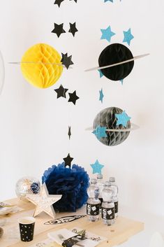 a table topped with drinks and decorations next to a wall mounted solar system on the wall